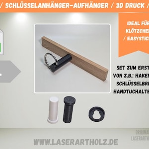Puede incluir: Un llavero de madera con un gancho negro y un anillo plateado. La imagen también muestra una clavija cilíndrica blanca y negra, y una pieza circular negra. El texto en la imagen dice "HAKEN / SCHLÜSSELANHÄNGER-AUFHÄNGER / 3D DRUCK / LASER".