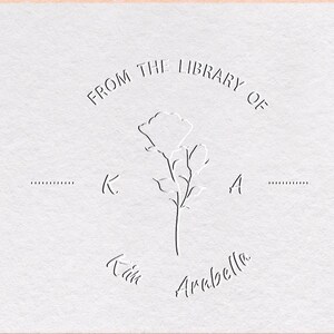Könnte beinhalten: Eine weiße Karte mit einem dekorativen Stempel, der eine stilisierte Blume und den Text "FROM THE LIBRARY OF K. A. Kim Arbella" zeigt.