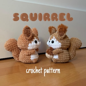 May include: Two handmade crochet squirrels in shades of brown and white are displayed. The word "SQUIRREL" is written above the squirrels, and "crochet pattern" is written below. The squirrels are on a wooden surface.