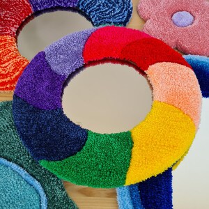 May include: A colorful, round mirror with a rainbow design. The mirror is surrounded by a variety of other colorful, fluffy shapes.