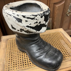 May include: A black and white Santa boot planter with a white rim and black boot. The boot is sitting on a woven wicker surface.