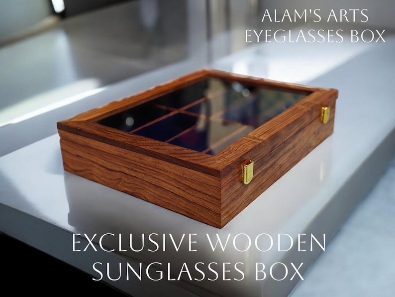K&ouml;nnte beinhalten: Eine rechteckige Aufbewahrungsbox aus Holz mit einem transparenten Glasdeckel und goldfarbenen Metallverschl&uuml;ssen. Das Innere ist in mehrere F&auml;cher unterteilt. Der Text ALAM'S ARTS EYEGLASSES BOX und EXCLUSIVE WOODEN SUNGLASSES BOX ist abgebildet.