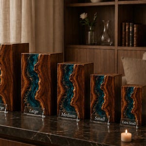 May include: A set of six rectangular wooden urns in varying sizes, each featuring a central vertical river-like inlay of teal resin with gold flecks. Clear acrylic labels in front of each urn read Extra Large, Large, Medium, Small, Extra Small, and Keepsake.
