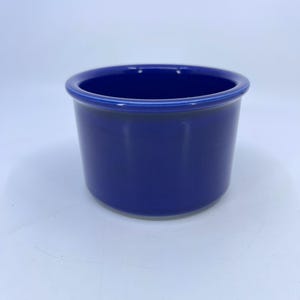 May include: A cobalt blue ceramic bowl with a rounded body and a slightly flared rim. The bowl has a smooth, glossy finish and is set against a white background. This versatile bowl is suitable for serving or as a decorative piece.