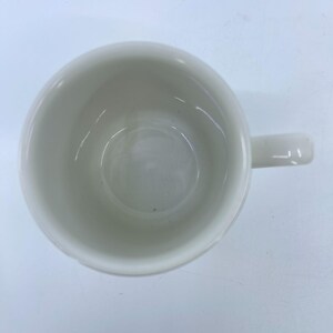 Puede incluir: Vista superior de una taza de cer&aacute;mica blanca con asa. La taza est&aacute; vac&iacute;a y limpia. El interior es liso y el asa tiene un dise&ntilde;o simple y curvado. La taza est&aacute; sobre una superficie blanca.