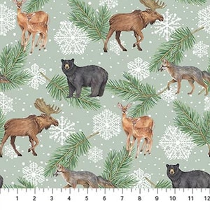 May include: Fabric featuring a repeating pattern of woodland creatures: deer, moose, bears, and wolves. Green pine branches and white snowflakes are scattered on a pale green backdrop. A ruler is visible along the bottom edge.