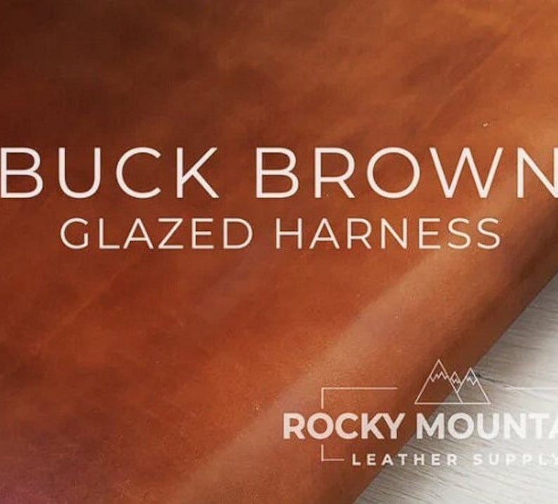 以下が含まれることがあります： 茶色の革のアップで、"BUCK BROWN GLAZED HARNESS"というテキストと、右下隅に"ROCKY MOUNTAIN LEATHER SUPPLY"のロゴがあります。