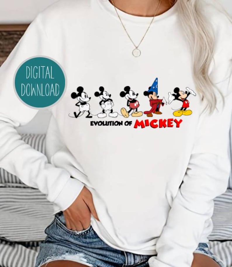 May include: White sweatshirt with a graphic of Mickey Mouse in different stages of his evolution. The text "Evolution of Mickey" is printed below the graphic.