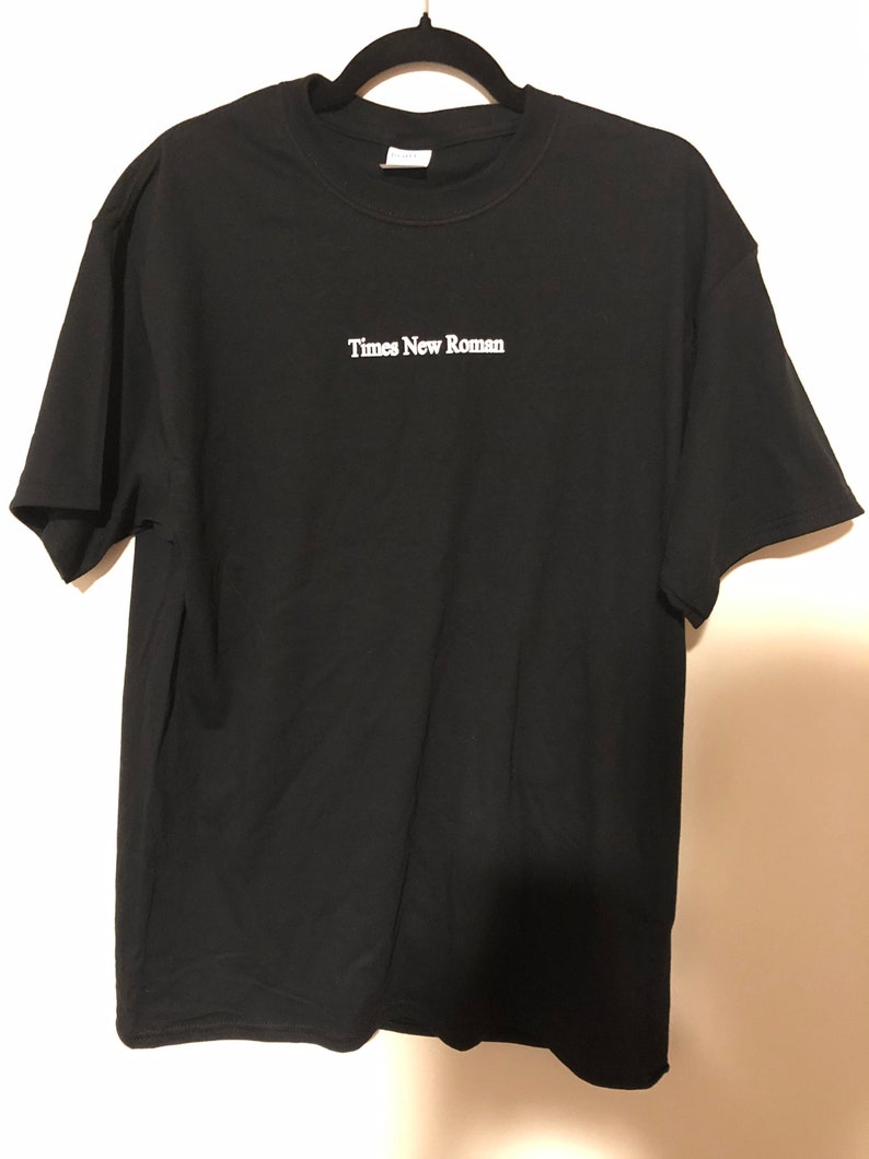 May include: Black t-shirt with white embroidered text that reads "Times New Roman".