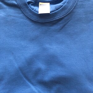 May include: A folded blue t-shirt with a white tag that says "PORT & CO."
