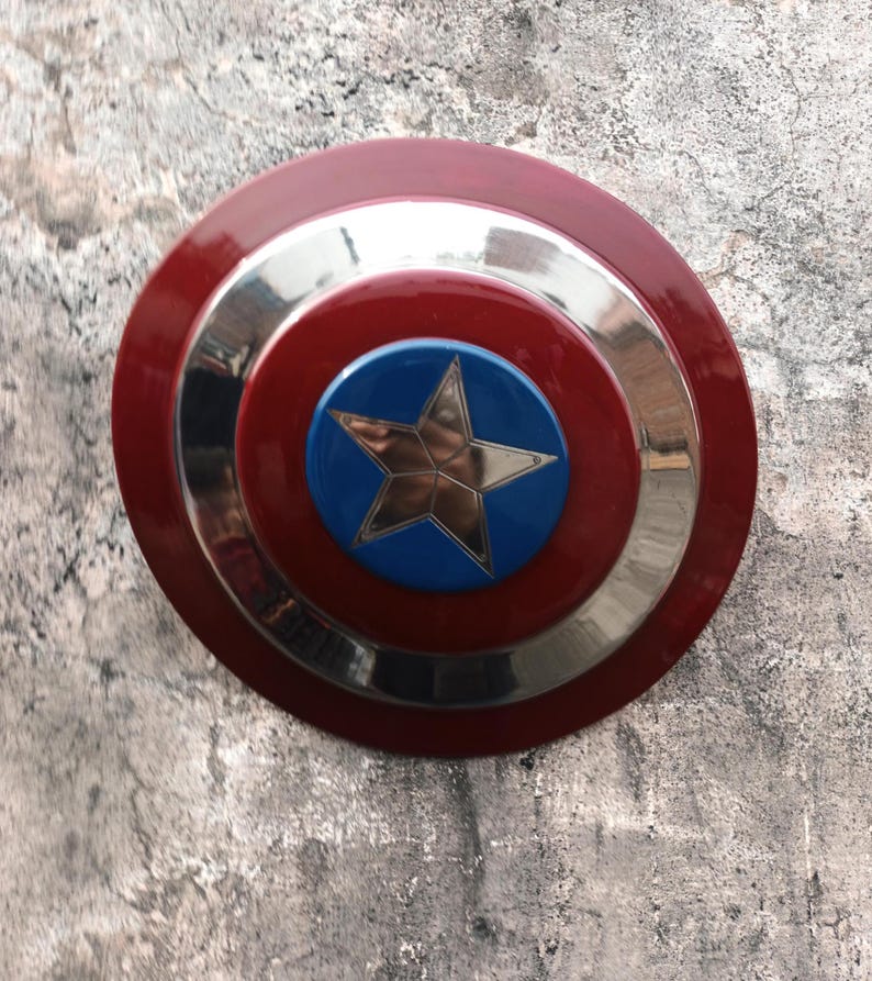 May include: A circular shield featuring a red outer ring, a silver band, and a blue central disc with a gold star. This shield is a replica of a famous superhero's emblem.
