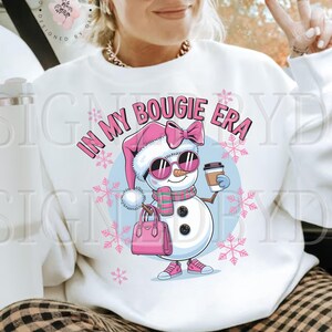May include: White sweatshirt with a pink and blue snowman graphic and the text "In My Bougie Era".
