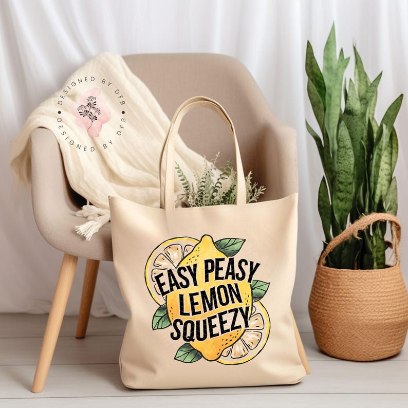 May include: A beige canvas tote bag with the text "Easy Peasy Lemon Squeezy" printed in black. The text is surrounded by a yellow lemon with green leaves.
