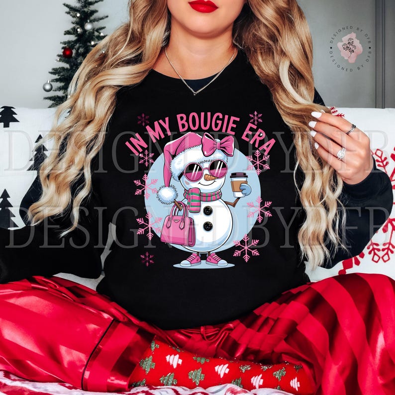 May include: Black sweatshirt with a pink and white snowman wearing sunglasses and holding a coffee cup. The snowman is holding a pink purse and the text "In My Bougie Era" is above the snowman.