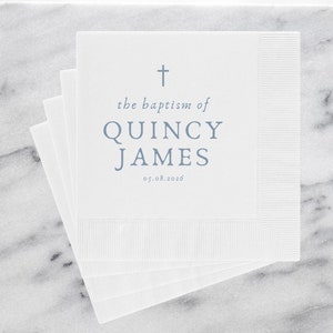 May include: White paper napkins with a blue cross, the text "the baptism of QUINCY JAMES 05.08.2026" and a marble background.