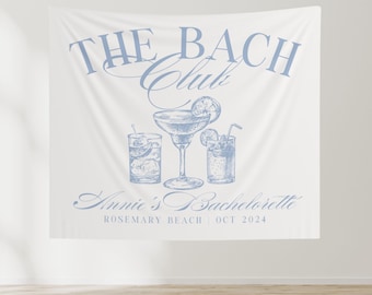 May include: A white banner with blue text that reads "The Bach Club" with a drawing of three cocktails. The text below the cocktails reads "Annie's Bachelorette Rosemary Beach | Oct 2024".