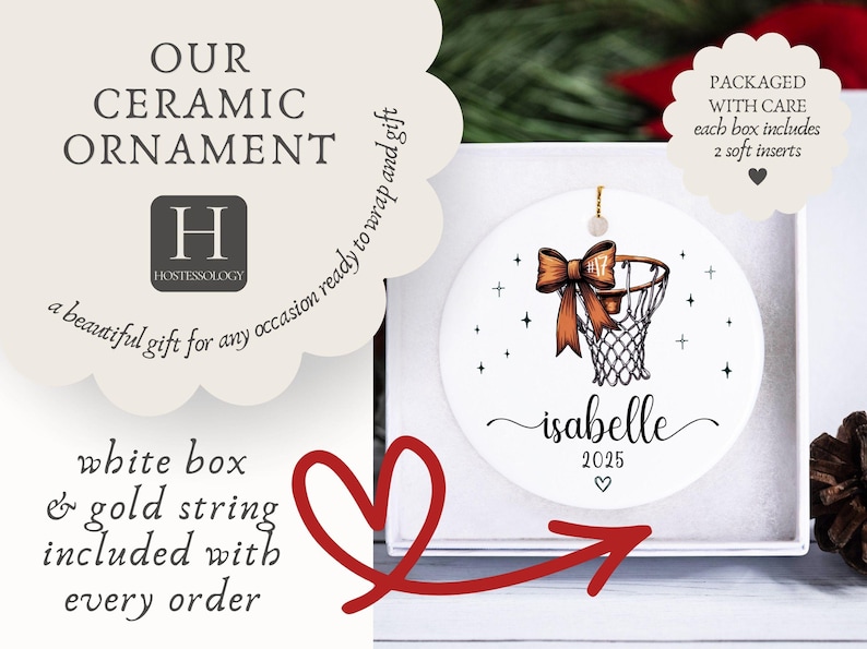 May include: White ceramic ornament with a basketball hoop design, a brown bow, and the name "Isabelle" with the year 2025. The ornament is packaged in a white box with a gold string. Text on the ornament reads "Our Ceramic Ornament" and "a beautiful gift for any occasion ready to wrap and gift."
