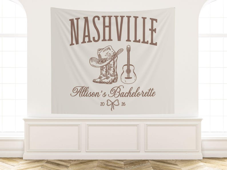 Op de afbeelding: Een beige wandtapijt met het woord "NASHVILLE" in bruine letters. Daaronder een schets van een cowboyhoed, laars en gitaar. De tekst "Allison's Bachelorette 20 26" is ook opgenomen.
