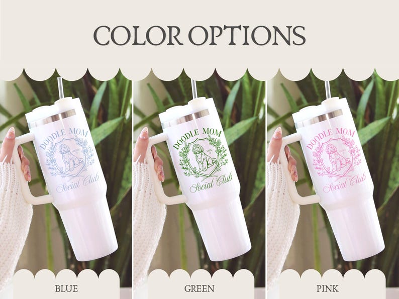 May include: White insulated tumbler with a handle, featuring the text "DOODLE MOM Social Club" in blue, green, and pink. The tumbler has a silver lid and a straw. The image shows three color options: blue, green, and pink.
