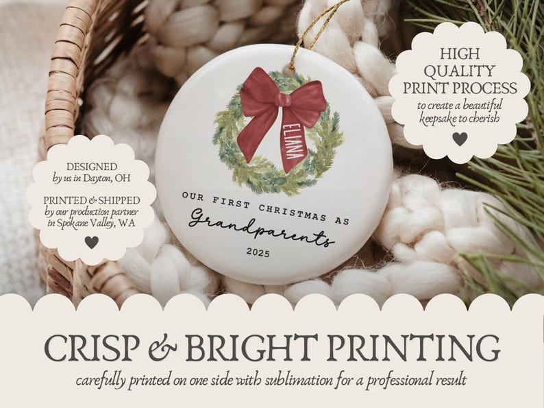 May include: A round white ceramic ornament featuring a green watercolor wreath with a red bow. The bow has the name Eliana printed on it. Below the wreath, the text reads Our First Christmas as Grandparents 2025 in black lettering.