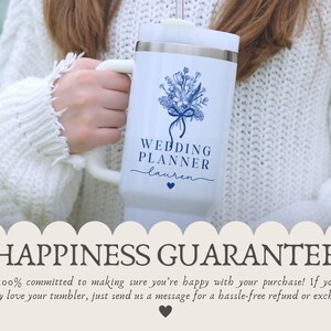 Puede incluir: Taza de viaje blanca con un dise&ntilde;o floral azul y el texto "WEDDING PLANNER lauren". La taza tiene un asa blanca y un borde plateado. Un coraz&oacute;n azul est&aacute; debajo del nombre. La taza la sostiene una persona que lleva un su&eacute;ter blanco.