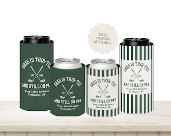 May include: Four beverage can coolers with a golf theme. The coolers are green and white, with the text "GREG IS THIR-TEE AND STILL ON PAR" and crossed golf clubs. The text also includes "Greg's 30th Birthday Scottsdale, AZ."