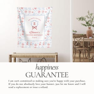 May include: A personalized banner with a floral pattern in red and blue, featuring the text "RED, WHITE, AND TWO!" and "Eleanor's SECOND BIRTHDAY 7-4-25". The banner is displayed above a wooden bench.