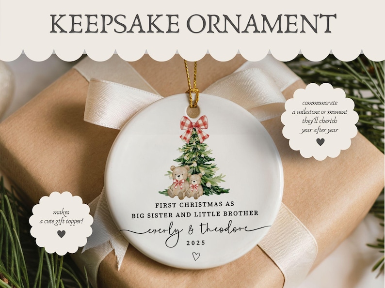 May include: A white ceramic Christmas ornament with a gold string, featuring a Christmas tree and two teddy bears. The ornament reads "First Christmas as Big Sister and Little Brother" with names and the year 2025. A red and white plaid bow tops the tree.