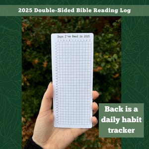 May include: A white card with a grid and the text "Days I've Read in 2025" printed on it. The card is being held by a hand in front of a green background. The text "Back is a daily habit tracker" is printed on the green background.