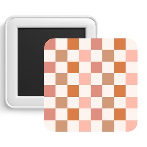 Könnte beinhalten: Ein weißer magnetischer Bilderrahmen mit einem herausnehmbaren Einsatz. Der Einsatz zeigt ein kariertes Muster mit abwechselnden Quadraten in Pfirsich, Hellbraun und Orange.