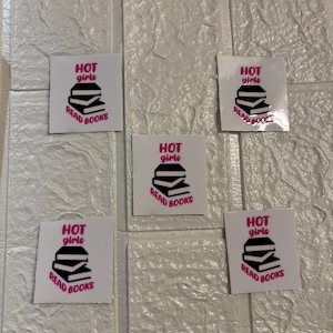 Könnte beinhalten: Fünf weiße quadratische Aufkleber mit schwarzem und rosa Text, der "HOT girls READ BOOKS" lautet, und einer schwarzen Illustration eines Bücherstapels.