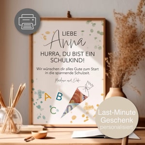 Puede incluir: Una impresión enmarcada con el texto "LIEBE Anna HURRA, DU BIST EIN SCHULKIND!" en escritura negra. La impresión incluye una ilustración colorida de un cono escolar y el texto "Last-Minute Geschenk personalisiert". El marco es de color marrón claro.