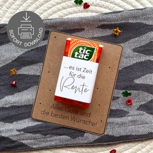 May include: A red and orange Tic Tac box with a white label that reads "...it is time for retirement" in German. The box is on a brown card with the text "Alles Gute und die besten Wünsche!" and decorative confetti.
