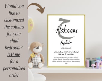 May include: A nursery print with a gold frame featuring the Arabic word "Hakeem" in grey calligraphy, meaning "wise, learned" in English. The print also includes the Arabic text "أعوذ بكلمات الله التامة من كل شيطان وهامَةِ وَمِن كُلِّ عَيْنٍ لاغةِ" and its English translation: "I seek protection for you in the Perfect Words of Allah from every devil and every beast, and from every envious blameworthy eye."
