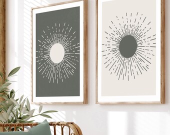 Könnte beinhalten: Zwei gerahmte Drucke mit minimalistischem Design. Die Drucke zeigen eine stilisierte Sonnenstrahlen mit einem Kreis in der Mitte. Ein Druck hat einen weißen Kreis auf einem dunkelgrauen Hintergrund, und der andere Druck hat einen dunkelgrauen Kreis auf einem hellbeigen Hintergrund.