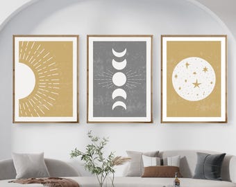 May include: Three minimalist wall art prints with a celestial theme. The prints feature a sun, a crescent moon, and a full moon with stars, all in white on a yellow background. The middle print has a gray background.