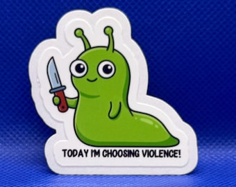 May include: A die-cut sticker featuring a cartoon green slug with large eyes, holding a small knife with a brown handle. Below the slug, the text reads "TODAY I'M CHOOSING VIOLENCE!" in black capital letters against a white background border.