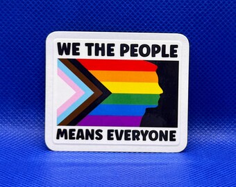 May include: A rectangular sticker featuring the text WE THE PEOPLE at the top and MEANS EVERYONE at the bottom in black capital letters. The center displays a pride flag with a silhouette of a human profile in black against the rainbow stripes.