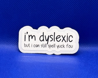May include: A white die-cut sticker with a scalloped edge featuring black text that reads, I'm dyslexic but i can still spell yuck fou. The sticker has a clean, simple design with a bold, sans-serif font for the main text and a smaller font below.