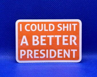 May include: A rectangular sticker with a vibrant orange background and rounded corners. The text I COULD SHIT A BETTER PRESIDENT is printed in bold, white, sans-serif capital letters across the center of the sticker, creating a high-contrast design.