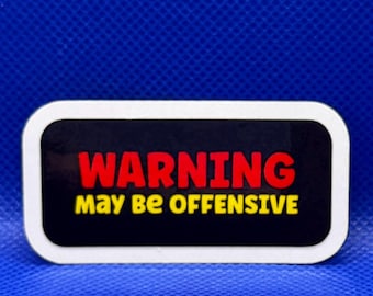 May include: A rectangular sticker with rounded corners featuring a black background and a white border. The text WARNING is printed in bold red capital letters, followed by the text MAY BE OFFENSIVE in yellow capital letters below it.