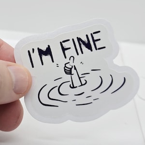 May include: A white die-cut sticker featuring a black line art illustration of a hand giving a thumbs-up while sinking into water, with the text I'M FINE printed in bold black capital letters above the hand, all on a white background.