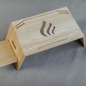 Puede incluir: Un soporte para portátil de madera con una extensión plegable. El soporte tiene un diseño recortado en forma de llama.