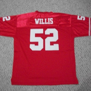 May include: Red football jersey with white stripes on the sleeves and white lettering on the back. The jersey has the number "52" and the name "WILLIS" on the back.