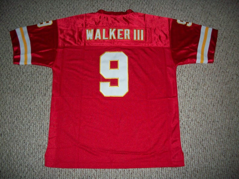 May include: Red football jersey with the name "WALKER III" across the shoulders and the number "9" on the back. The jersey has white and yellow stripes on the sleeves.