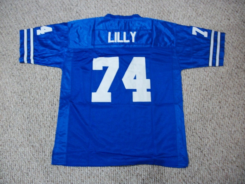 Op de afbeelding: Een blauw voetbaltenue met witte letters. Het nummer "74" staat op de achterkant van het tenue, met de naam "LILLY" erboven.