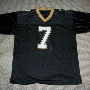 May include: Black football jersey with a white number "7" on the front. The jersey has gold trim around the neck and sleeves.