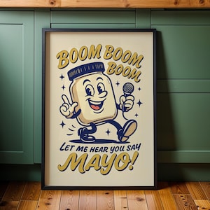 Może przedstawiać: Oprawiony plakat z postacią z kreskówki słoika majonezu trzymającą mikrofon i pokazującą znak pokoju. Tekst brzmi "BOOM BOOM BOOM" i "LET ME HEAR YOU SAY MAYO!" w stylu retro, z czarną ramą.
