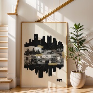 Op de afbeelding: Een ingelijste kunstdruk met een zwart-wit collage van een skyline en architectonische elementen. De print bevat het woord "PIT" onderaan. Het kunstwerk wordt tentoongesteld in een lichte ruimte met een trap en een plant in een pot.