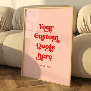 Peut inclure: Une affiche encadrée avec un fond rose et un cadre doré. L'affiche comporte un texte rouge qui dit "Your Custom Quote here" et "THE AUTHOR" en bas.